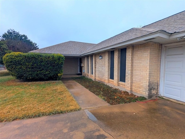 entrance to property with a garage and a lawn