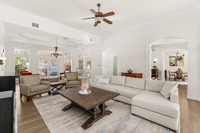 living room with a raised ceiling, crown molding, ceiling fan with notable chandelier, and hardwood / wood-style floors