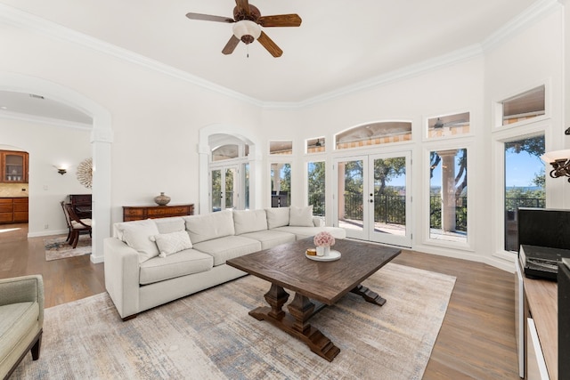 living room with wood-type flooring, ornamental molding, french doors, and a high ceiling