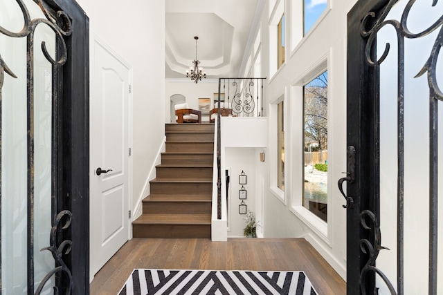 entrance foyer with dark wood-type flooring, crown molding, and a chandelier