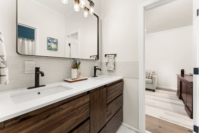 bathroom featuring hardwood / wood-style flooring, crown molding, vanity, and backsplash