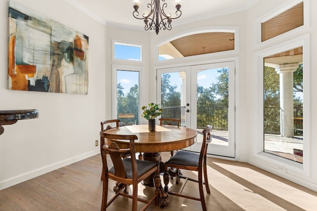 dining area with ornamental molding, a chandelier, light wood-type flooring, and french doors