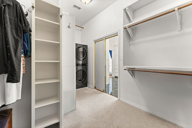 spacious closet with stacked washer and dryer and carpet