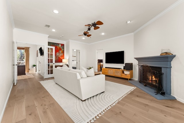 living room featuring ornamental molding, ceiling fan, and light wood-type flooring