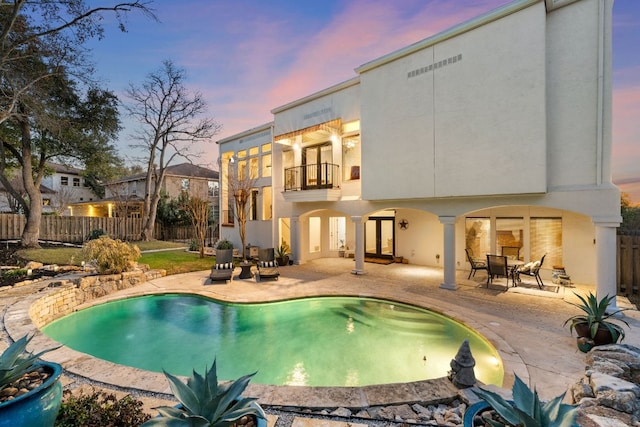 pool at dusk featuring a patio