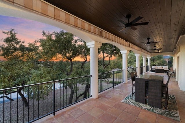 patio terrace at dusk with a balcony, outdoor lounge area, and ceiling fan