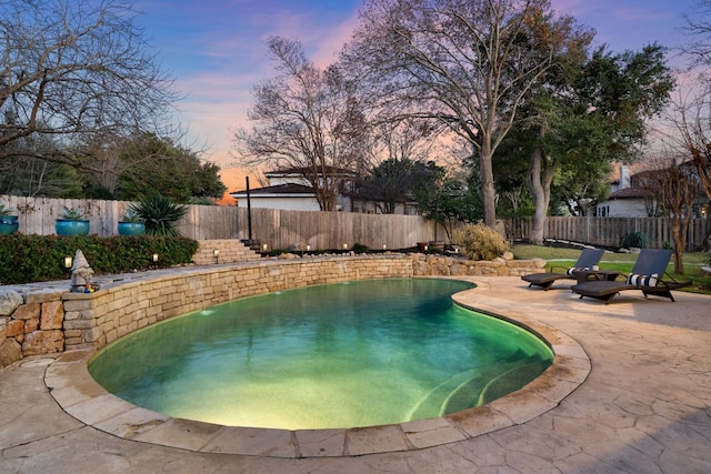 pool at dusk with a patio area