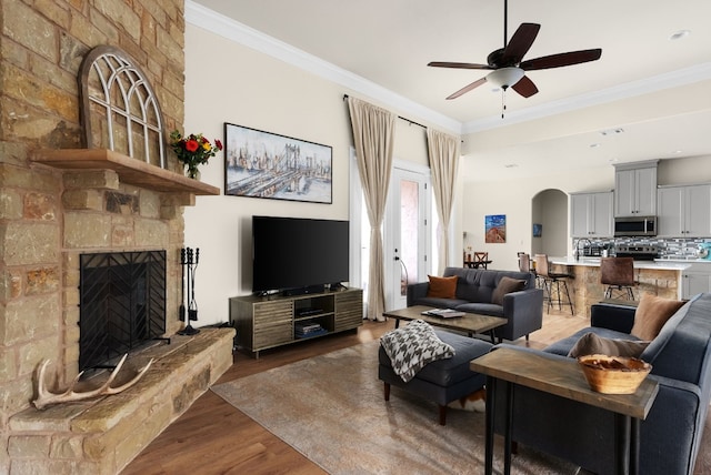 living room featuring a fireplace, dark wood-type flooring, ornamental molding, and ceiling fan