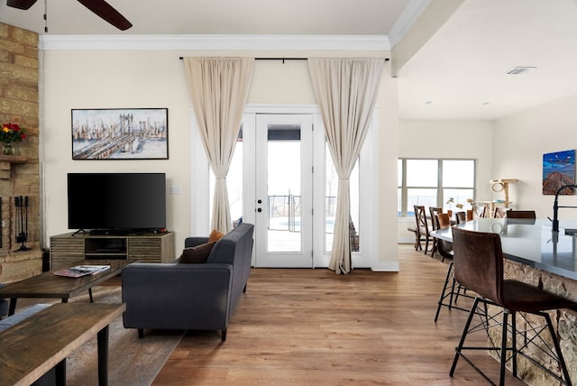 living room with hardwood / wood-style floors, crown molding, and ceiling fan