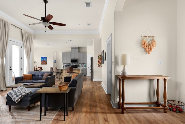 living room featuring hardwood / wood-style floors, crown molding, and ceiling fan