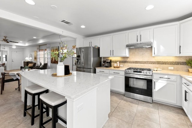 kitchen featuring white cabinetry, light stone countertops, a center island, and appliances with stainless steel finishes