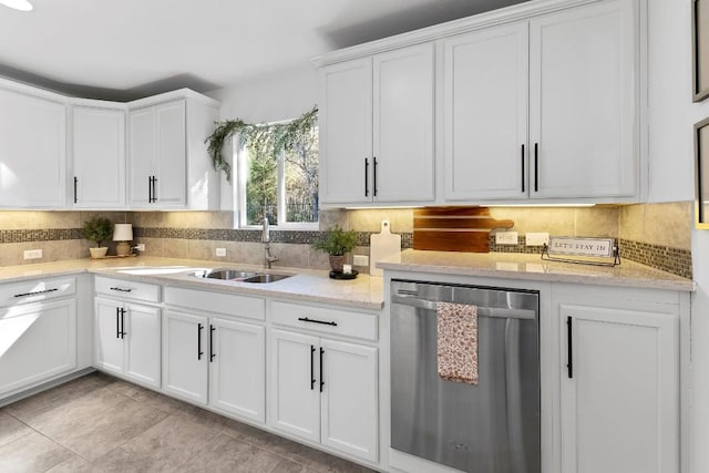 kitchen featuring sink, dishwasher, white cabinetry, light stone counters, and decorative backsplash