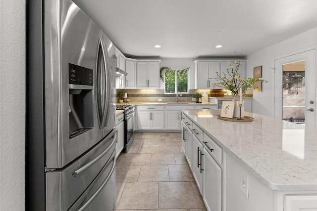 kitchen featuring sink, white cabinets, decorative backsplash, light stone counters, and stainless steel appliances