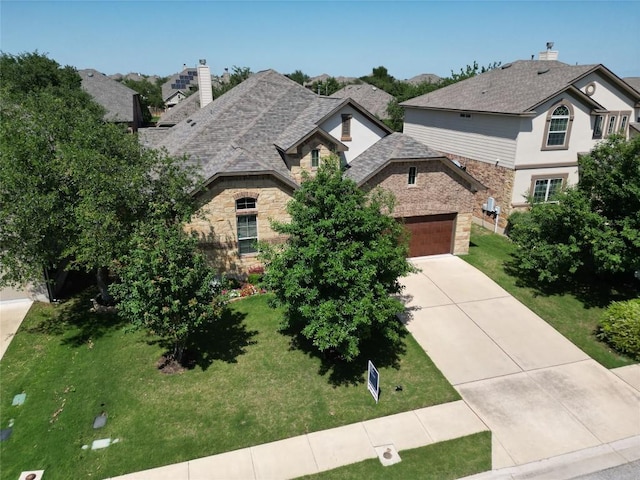 french country style house with stone siding, a chimney, driveway, and a front lawn