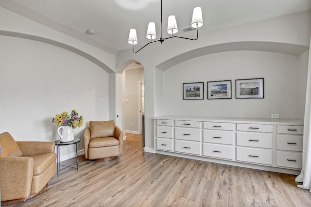 living area with light hardwood / wood-style floors and a notable chandelier