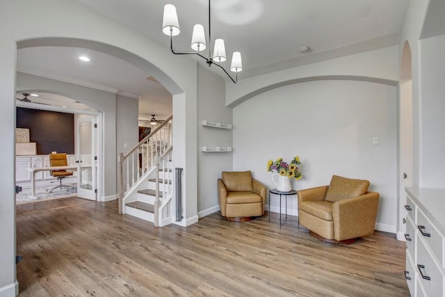 sitting room with ceiling fan with notable chandelier and light hardwood / wood-style flooring