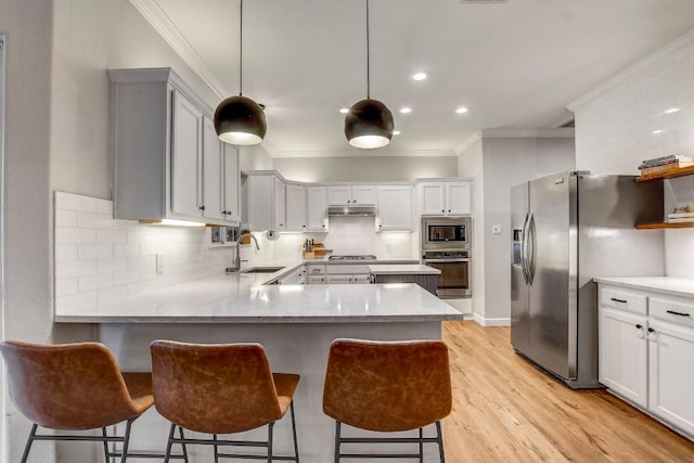 kitchen featuring appliances with stainless steel finishes, pendant lighting, ornamental molding, light hardwood / wood-style floors, and kitchen peninsula