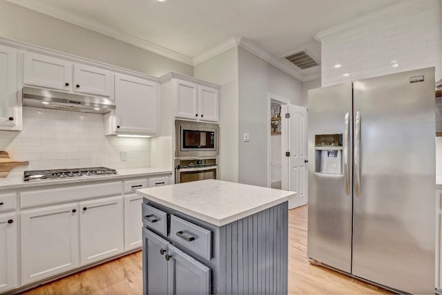 kitchen with ornamental molding, stainless steel appliances, a center island, and white cabinets