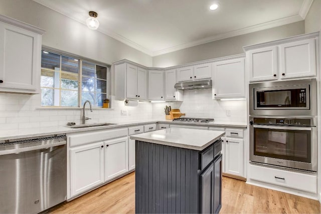 kitchen with sink, crown molding, appliances with stainless steel finishes, white cabinetry, and a kitchen island