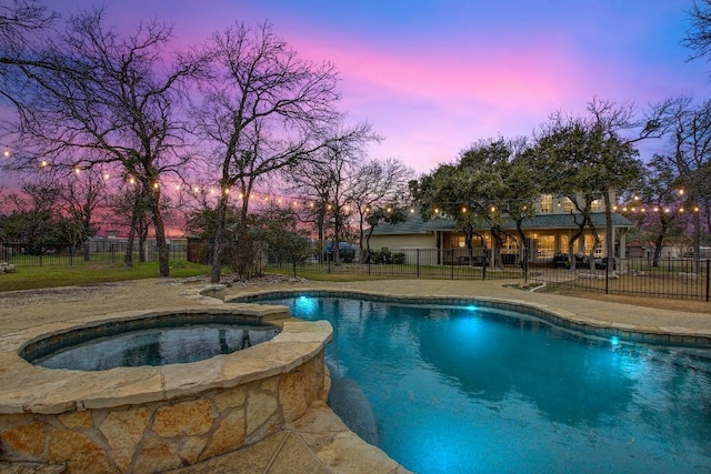 pool at dusk with an in ground hot tub