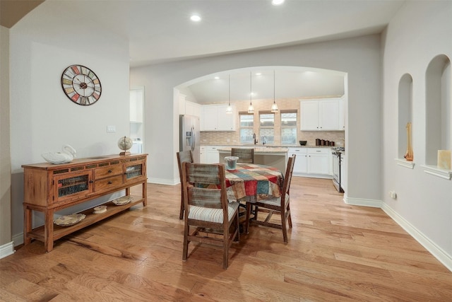 dining room featuring lofted ceiling, sink, and light hardwood / wood-style floors