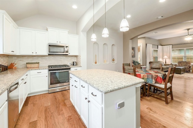 kitchen featuring a kitchen island, pendant lighting, white cabinets, stainless steel appliances, and light stone countertops