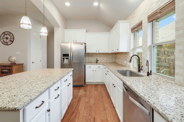 kitchen with sink, white cabinetry, stainless steel appliances, decorative light fixtures, and light wood-type flooring