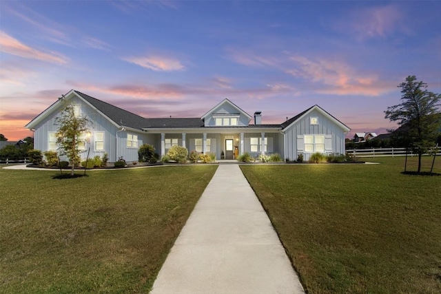 view of front of home with board and batten siding, a yard, and fence