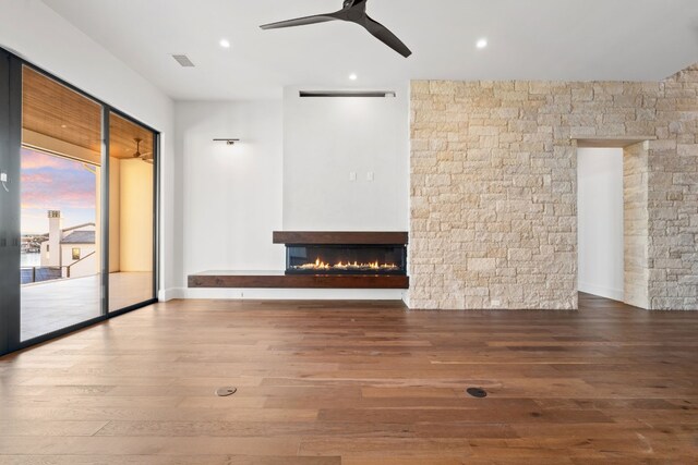 1409 Apache Tears, Horseshoe Bay, TX 78657 - empty room featuring wood finished floors, ceiling fan, a warm lit fireplace, and recessed lighting
