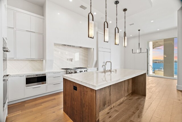 1409 Apache Tears, Horseshoe Bay, TX 78657 - kitchen with modern cabinets, light wood-style flooring, recessed lighting, tasteful backsplash, and an island with sink