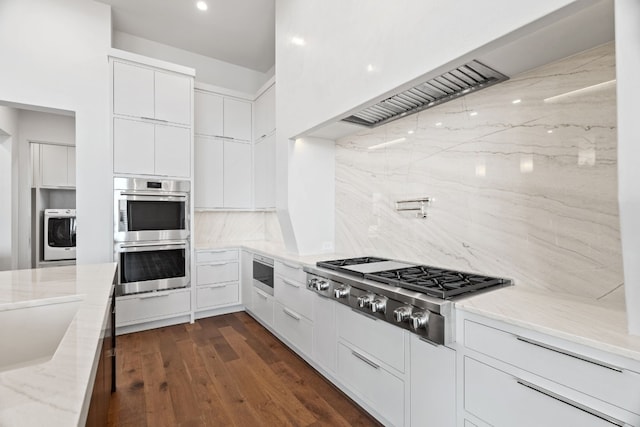 kitchen with washer / dryer, white cabinets, decorative backsplash, stainless steel appliances, and light stone countertops