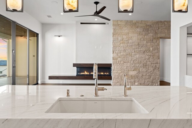 1409 Apache Tears, Horseshoe Bay, TX 78657 - kitchen featuring a ceiling fan, light stone counters, a lit fireplace, and recessed lighting