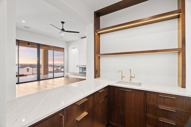 kitchen with sink, light stone countertops, and ceiling fan