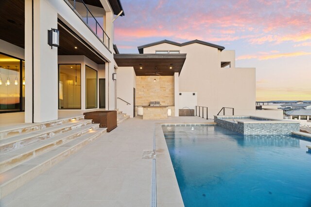 1409 Apache Tears, Horseshoe Bay, TX 78657 - pool at dusk featuring an outdoor kitchen, a pool with connected hot tub, a patio, and entry steps