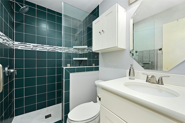 bathroom with vanity, toilet, and tiled shower