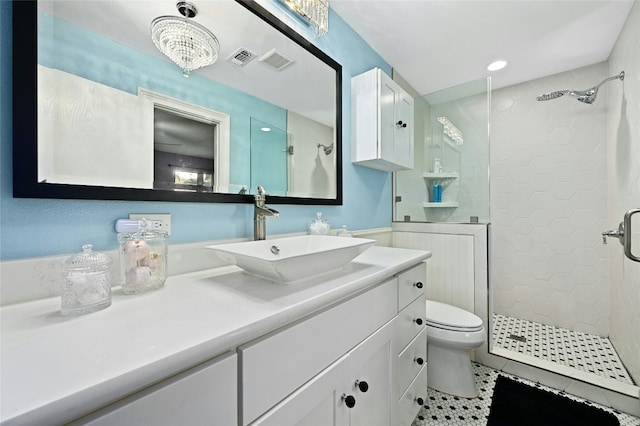 bathroom with tiled shower, tile patterned floors, toilet, and vanity