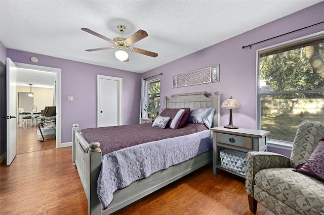 bedroom with multiple windows, dark wood-type flooring, and a textured ceiling