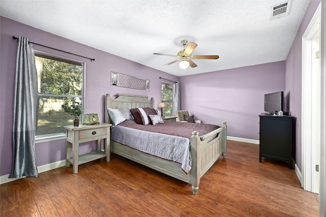 bedroom featuring dark hardwood / wood-style flooring, ceiling fan, and a textured ceiling