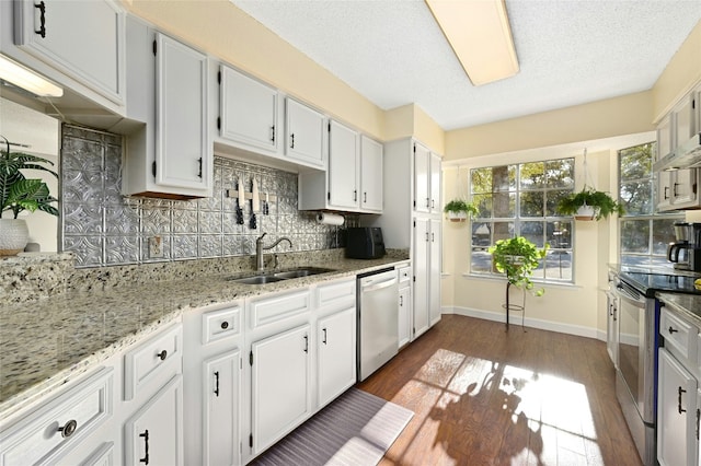 kitchen with sink, white cabinetry, tasteful backsplash, stainless steel appliances, and light stone countertops