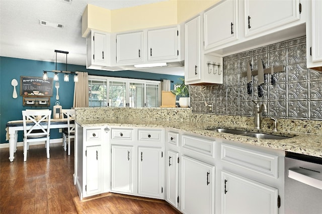 kitchen with hanging light fixtures, light stone countertops, stainless steel dishwasher, and white cabinets