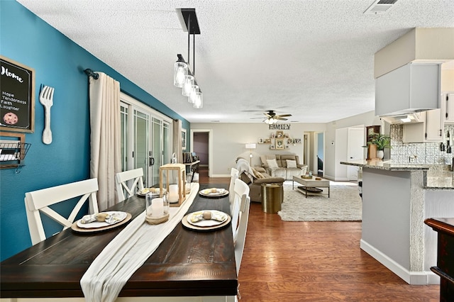 dining room featuring dark wood-type flooring, ceiling fan, and a textured ceiling