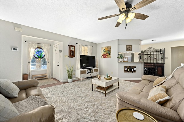 living room with ceiling fan, light hardwood / wood-style floors, and a textured ceiling