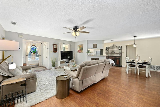 living room featuring hardwood / wood-style floors, a textured ceiling, and ceiling fan