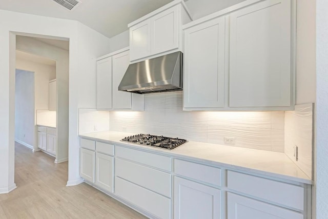 kitchen with white cabinetry, stainless steel gas stovetop, tasteful backsplash, and light wood-type flooring