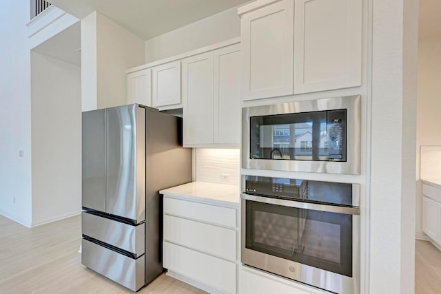 kitchen with white cabinetry, light hardwood / wood-style flooring, and appliances with stainless steel finishes