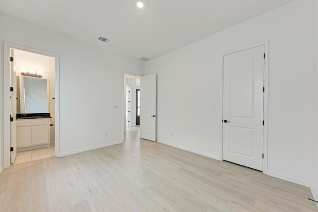 unfurnished bedroom featuring ensuite bathroom and light hardwood / wood-style floors