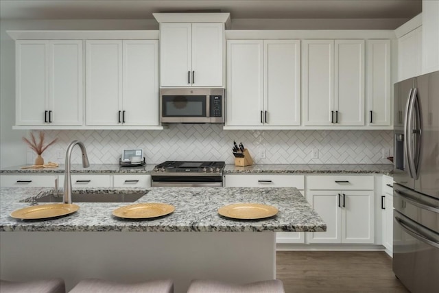 kitchen with light stone countertops, appliances with stainless steel finishes, and white cabinets