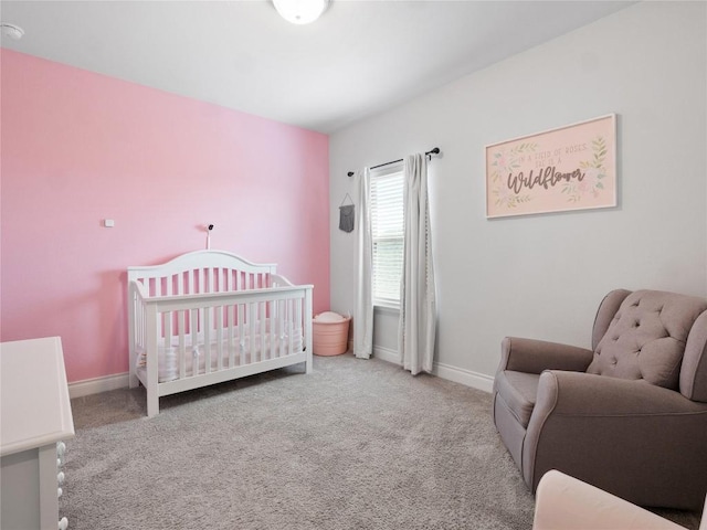 carpeted bedroom featuring a crib and baseboards