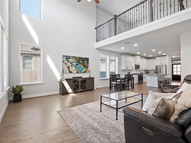 living room with a ceiling fan, recessed lighting, light wood-style flooring, and baseboards