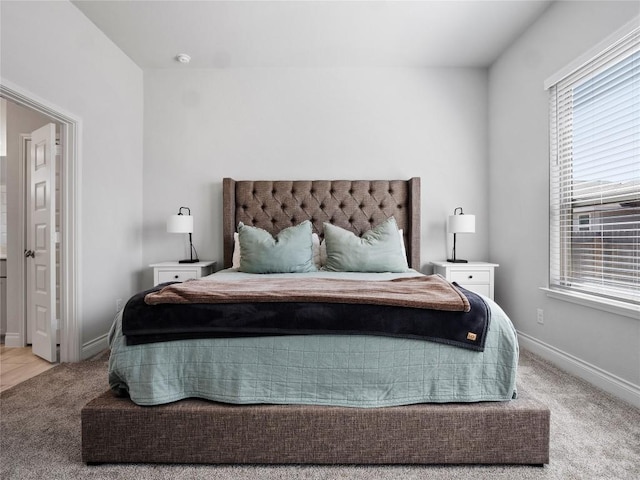 bedroom featuring baseboards, multiple windows, and light colored carpet